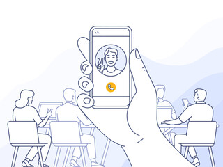 An individual holds a phone displaying a video call interface, set against a backdrop of colleagues engaged in a productive meeting, emphasizing modern communication methods.