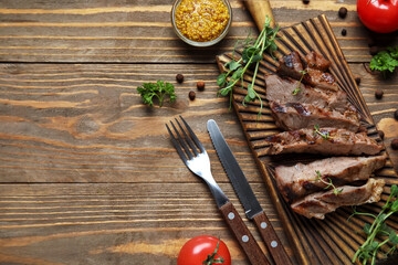 Cut grilled steak with microgreen, mustard and cutlery on wooden background