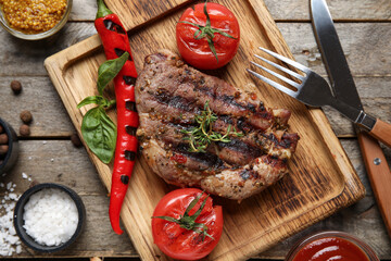 Tasty grilled steak with tomatoes and chilli pepper on wooden background