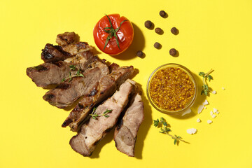 Cut grilled steak with tomato, Dijon mustard and allspice on yellow background