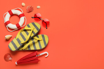 Striped flip-flops with sea shells, sunglasses, umbrella and lifebuoy on red background