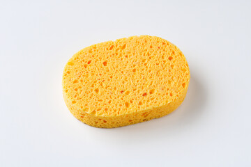A single yellow cellulose sponge with a porous texture, used for cleaning or bathing, isolated on a white background.