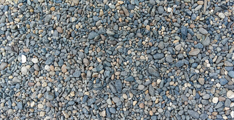 A high-resolution, full-frame background of natural gray and light-colored river pebbles. Diverse sizes and smooth texture for a clean, organic, and versatile surface design.