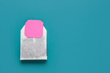 Tea bag with pink label on turquoise background