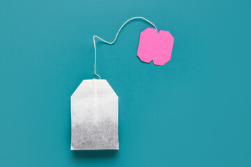 Tea bag with pink label on turquoise background