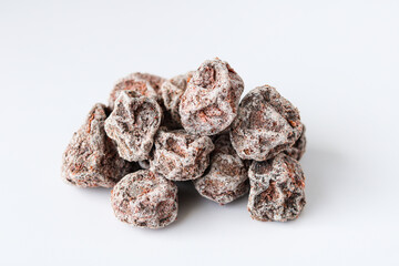 Closeup of a pile of salted preserved plums (kiamboy asin asem) coated with a powdery white layer, isolated on a white background.