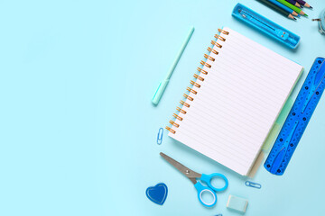 Notebook with different stationery on blue background