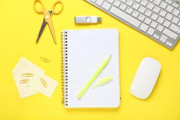 Notebook with computer keyboard, mouse and different stationery on yellow background