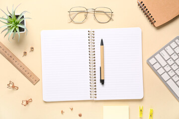 Notebooks with computer keyboard, eyeglasses and different stationery on beige background