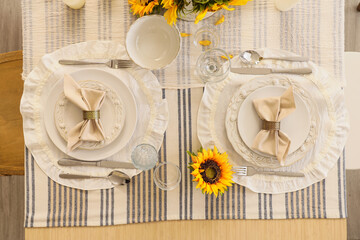 Elegant table serving with plates, folded napkins and beautiful sunflowers, top view