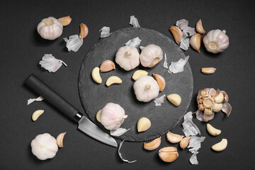 Board with fresh garlics on black background