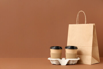 Paper bag with coffee cups on brown background