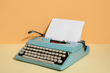Vintage typewriter with blank paper sheet on color background
