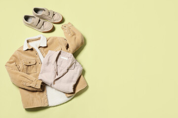 Stylish children's jacket with shirt and sneakers on green background