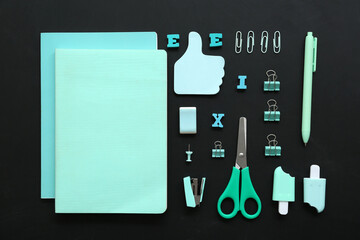 Different stationery supplies on black chalkboard