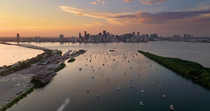 Biscayne Bay in Miami city in Florida. Harbor with many yachts and motor boats. Sunset over city skyline with high-rise buildings in downtown.