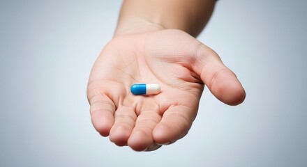 Holding a blue and white capsule, a symbol of health, wellness, and medicine for your marketing and advertising needs to promote pharmaceutical products