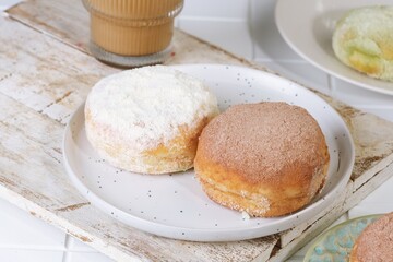 Indonesian style milk donut with vanilla milk powder topping on white plate, delicious homemade dessert bread snack.