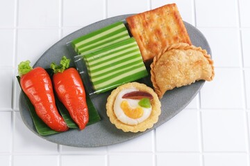 A variety of traditional Indonesian market snacks arranged on a plate, including steamed cake, fried pastry, and fresh vegetables.