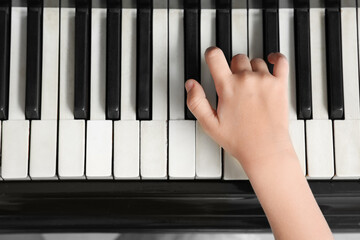 Cute little girl playing grand piano at home, top view