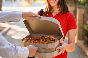 Female courier delivering pizza to man outdoors