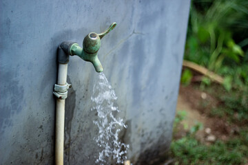Old outdoor water faucet with running water, symbolizing access to clean water, sustainability, and everyday rural life. Natural light and authentic texture.