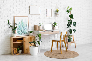 Interior of office with workplace, blank frames and houseplants