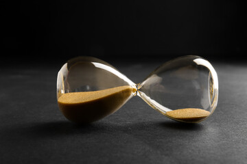 Hourglass with yellow crystals on black background. Time management concept