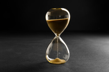Hourglass with yellow crystals on black background. Time management concept