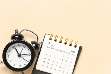 Calendar with alarm clock on beige background