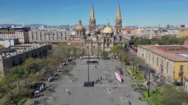Aerial drone shot advancing at medium height through Plaza Tapatia showing people, trees and buildings