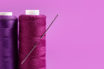 Spools of thread with needle on purple background