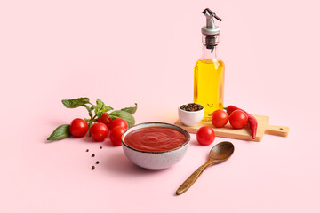 Bowl of tasty tomato sauce and different ingredients on pink background