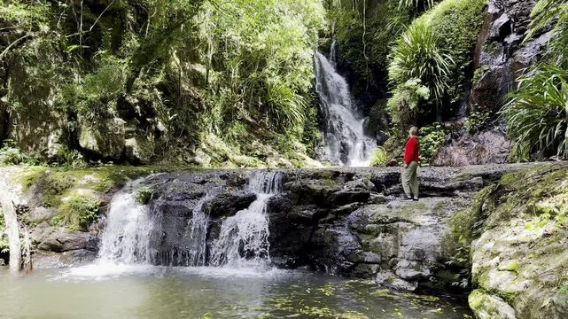 Adventurous hiker girl stands near fairytale Elabana Falls hidden in lush ancient Gondwana rainforest, Lamington National Park, O&rsquo;Reilly&rsquo;s section, near Gold Coast and Brisbane, Queensland, Australia