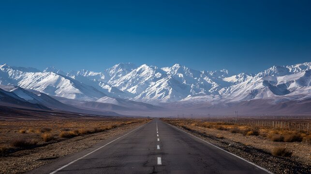 Open asphalt road leads to majestic snow-capped mountains under a clear blue sky. - Powered by Adobe