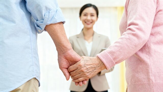 real estate agent senior clients concept. Elderly couple holding hands with a smiling professional in the background.