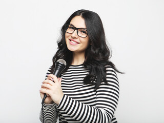 Lifestyle, party and people concept: young woman wearing striped shirt , holding microphone, singing and smiling.