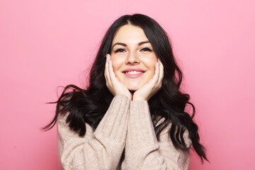Attractive caucasian smiling brunette woman over pink background.