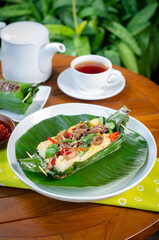 Grilled rice with stir-fried salted squid, wrapped in banana leaves, a traditional Indonesian dish.
