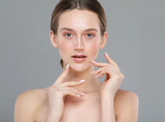 A beautiful young woman with a perfect face touches her facial skin with her fingertips.