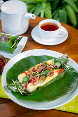 Grilled rice with stir-fried salted squid, wrapped in banana leaves, a traditional Indonesian dish.