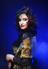 Fashionable woman with creative makeup and hairstyle posing on dark blue background.