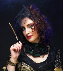 A stylish woman in a vintage hat and chic clothes holds a cigarette holder, preparing to smoke.