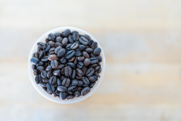 Roasted coffee beans full in glass on wood table