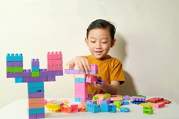 Fototapeta premium A focused young boy assembling colorful plastic blocks during creative playtime. 