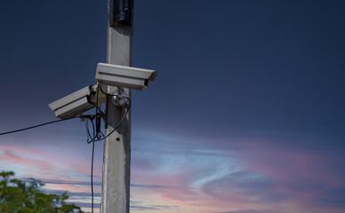 Two outdoor bullet-style CCTV surveillance cameras mounted on a metal utility pole, providing...