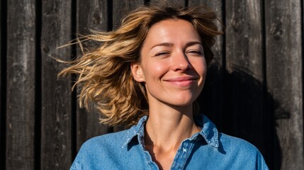 Fototapeta premium Woman blowing wind-kissed hair, smiling, outdoors, daylight.