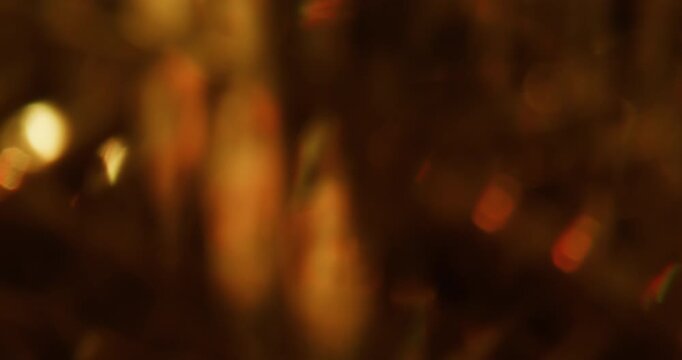 Blur twinkle. Color light flare. Defocused orange glare radiant illuminated dazzle flash on abstract optical visual dark black art bokeh background.