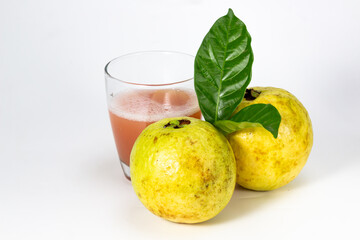 A refreshing glass of guava juice sits beside two whole guavas, one adorned with a vibrant green.