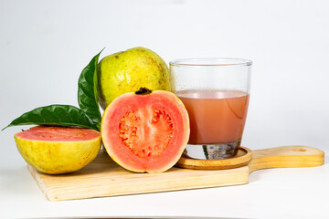 Fresh guava fruits and juice are arranged on a wooden board, showcasing the vibrant colors and.